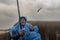 Ijmuiden/Holland - October 06 2019: Fisherman fishing in raincoat under rain and seagull flying in background