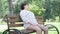 Ill Caucasian senior woman having heart attack sitting on bench in summer park as people passing by. Portrait of