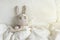 Ill Grey toy rabbit with thermometer and plaster on head in white bedroom.