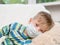 Ill little boy in medicine health-care mask lying on bed