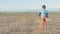 Illegal migration concept of one poor little boy with plush toy walking alone in hot desert on state border with high fence with r