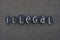 Illegal word composed with black colored stone letters over black volcanic sand