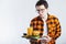 Illness sad young man in shirt put hand on pain abdomen, stomach-ache, standing and holding burger isolated on white background. P