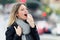 Illness young woman using a analgesic spray to soften the throat in the street.