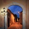 Illuminated alleyway with arched gate and lantern