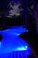 Illuminated blue light pool with palm trees