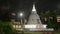 Illuminated Buddhist pagoda at night. Sacred temple bright lights, prayer flags flutter. Peaceful spiritual retreat