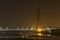 Illuminated cable-stayed bridge under construction with a tower crane over the Yamuna River at night. Signature Bridge. Delhi