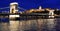 Illuminated chain bridge and national gallery at night in Budapest