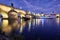 Illuminated Charles Bridge reflected in Vltava river at night in Prague