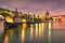 Illuminated Charles Bridge is reflected in Vltava river at night in Prague