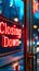 Illuminated Closing Down sign hanging in a storefront window at dusk, signaling the end of business operations, with city lights