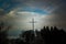 illuminated cross against a blue sky surrounded by trees