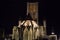 Illuminated facade of Saint Nicholas` Church Sint-Niklaaskerk during the night with the clock tower of Former Post Office at th