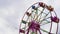 Illuminated Ferris wheel with multicolour cabins turning in amusement park.