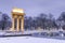 Illuminated General Bem Monument in Tarnow, Poland. Magical Winter Snowfall in City Park and Pond at Twilight