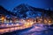 illuminated ice rink near a mountain resort at night