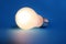 Illuminated lightbulb on blue background