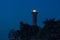Illuminated lighthouse in Savudrija, Istria, Croatia with silhouettes of trees at night