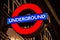 Illuminated London Underground tube sign at night.