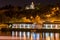 Illuminated marina building with colored reflections in water at night in Prague