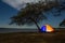 Illuminated orange camping tent under the tree