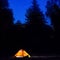 Illuminated orange tent at night in the forest