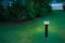 Illuminated outdoor light in apartment garden at twilight, evening.