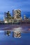 Illuminated petrochemical production plant at twilight with dramatic clouds reflected in a pond, Antwerp, Belgium.