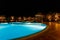 Illuminated pool at night with tropical palms