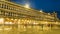 Illuminated Procuratie building and many people in Saint Mark Square at night