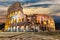 Illuminated Roman Coliseum under the clouds at sunrise, Italy