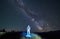 Illuminated spaceman fresh from the space standing in the middle of mountain meadow holding guitar, under Milky Way