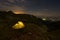 An illuminated tent above a valley