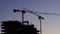 Illuminated tower crane works at the construction site of a multi-storey building