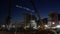 Illuminated tower cranes work at a construction site at night