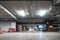 Illuminated underground car parking garage interior under modern mall with lots of vehicles