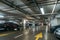 Illuminated underground car parking interior under modern mall with lots of vehicles and arrows on floor