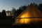 Illuminated yellow camping bell tent at night