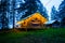 Illuminated yellow camping bell tent at night. Glamping bell tent glows at forest