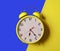 Illuminating color Retro style alarm clock on blue and yellow background