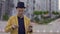 Illusionist in hat and yellow jacket skillfully moving playing cards in hands