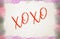 Illustration with a background of watercolor brush strokes with the word XoXo in red