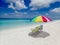 An illustration of a colorful beach umbrella and chairs by ocean waves lapping on the beach on a beautiful sunny day along the