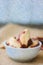 Illustration of heap of brazil nuts in white ceramic bowl over the brown fabric.