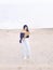 Illustration image of blurry painting of calm brunette girl walking alone on sand beach with bouquet of fluffy spikes