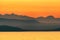 Illustration of a mountain range behind a seascape at sunset