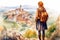 Illustration in a watercolor style. Traveling girl with a backpack looking down from hill to beautiful town