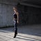 Illustration of a young woman adjusting her ponytail at the entrance of a subway tunnel in early morning light