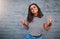 Im just here to spread some love and peace. Portrait of a young woman showing the peace sign against a grey wall.